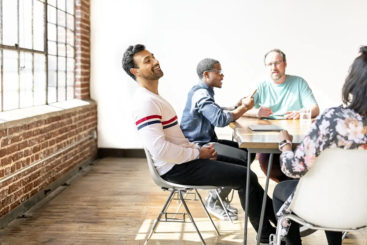 A small team talking through a project together around a table in a bright office