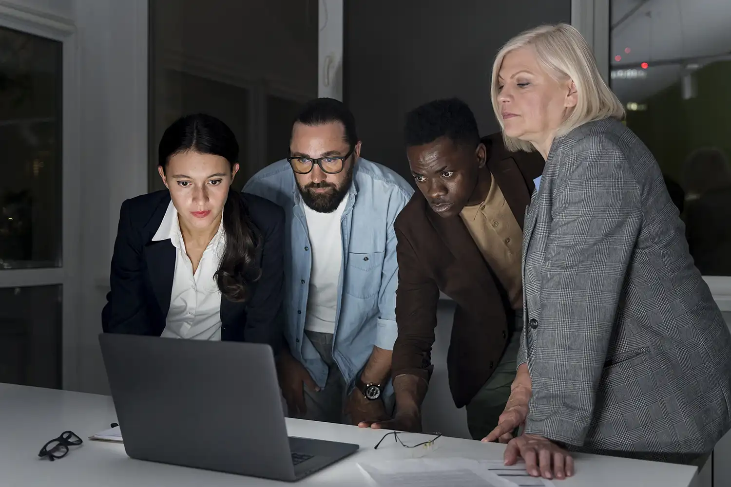 A team gathered round a laptop in the evening, working through an investigation together